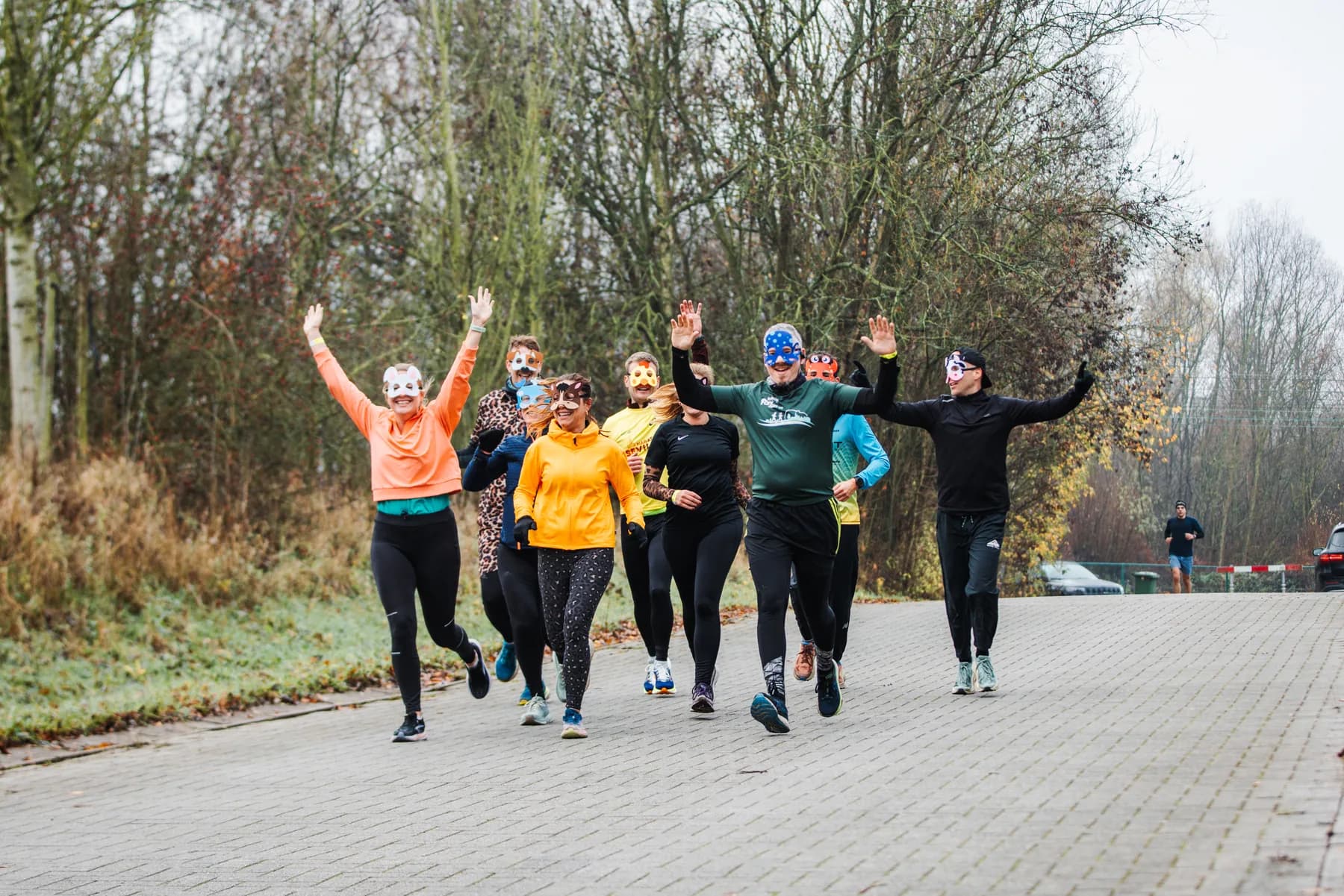 Lopers met dierenmaskers en de armen in de lucht