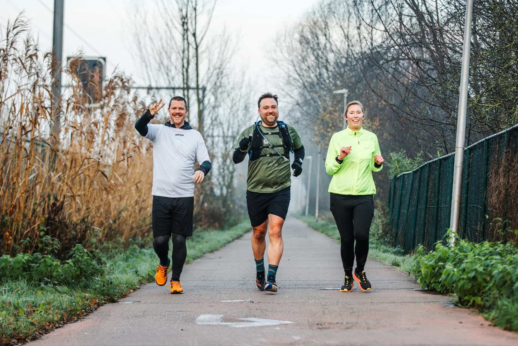 Drie lachende lopers op het jaagpad