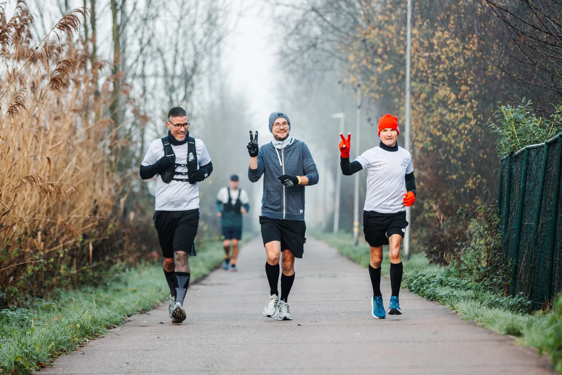 Drie lopers met een peace-teken in de mist